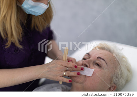 A blonde woman with short hair lies on a cosmetic bed covered with a quilt. 110075389
