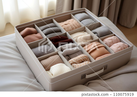 A box with dividers for categorized storage with neatly laid out clothes 110075919