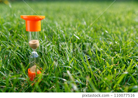 Hourglass on green grass Hourglass on green grass 110077516