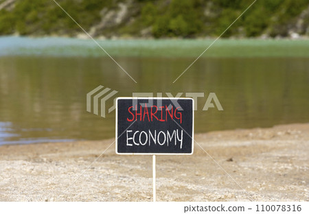 Sharing economy symbol. Concept words Sharing economy on beautiful black chalk blackboard. Beautiful sand beach mountain lake background. Business sharing economy concept. Copy space. Sharing economy symbol. Concept words Sharing economy on beautiful black chalk blackboard. Beautiful sand beach mountain lake background. Business sharing economy concept. Copy space. 110078316