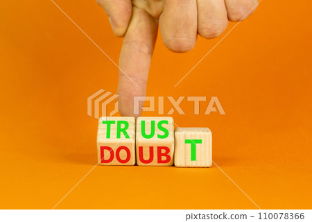 Trust or doubt symbol. Turned wooden cubes and changed the word doubt to trust or vice versa. Beautiful orange table background, copy space. Businessman hand. Business and trust or doubt concept. 110078366