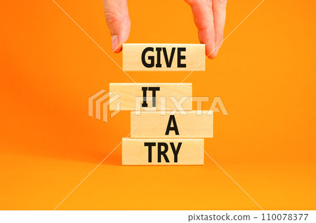 Give it a try symbol. Concept word Give it a try on beautiful wooden block. Beautiful orange table orange background. Businessman hand. Business give it a try concept. Copy space. 110078377