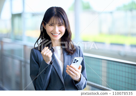 Young business woman in a suit looking at smartphone Young business woman in a suit looking at smartphone 110078535