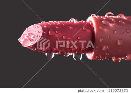 Red lipstick with water drops on a dark background. Red lipstick with water drops on a dark background. 110078573