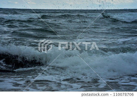 rocky seashore, surf and waves are broken by splashes and foam rocky seashore, surf and waves are broken by splashes and foam 110078706