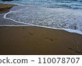 traces of bare feet on the sand on the beach, waves flooding our footprints and time passing quickly 110078707