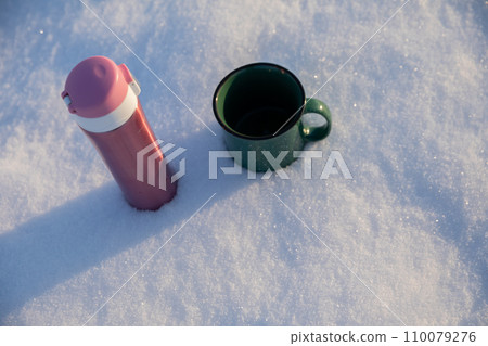 Two mugs standing in the snow as seen from above. 110079276