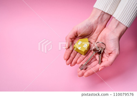 Female hands, a small wooden house and keys as an idea for investing in your own home and achieving the goal of buying real estate Female hands, a small wooden house and keys as an idea for investing in your own home and achieving the goal of buying real estate 110079576
