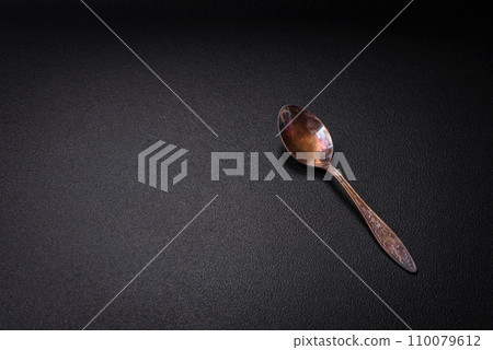 Empty metal spoon on dark textured concrete background Empty metal spoon on dark textured concrete background 110079612