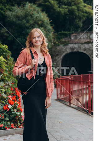 Happy blonde 30s woman enjoying summer holidays. Concept of vacation and travelling. Varenna, Italy. Lake Como. Sexy carefree woman posing on park background. 110079878