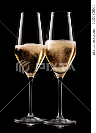Pair crystal-clear flute glass of champagne isolated on black background Pair crystal-clear flute glass of champagne isolated on black background 110080063