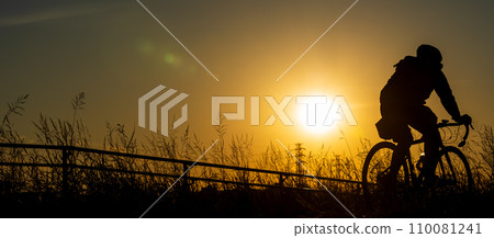 Sunset and silhouette of a person riding a road bike Sunset and silhouette of a person riding a road bike 110081241