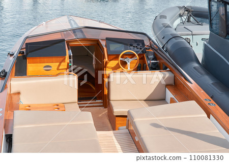 Close-up view of a relaxation area on the open teak deck of an expensive motorboat at sunny day, Monaco yacht show, large boat exhibition, wealth life, table and chairs Close-up view of a relaxation area on the open teak deck of an expensive motorboat at sunny day, Monaco yacht show, large boat exhibition, wealth life, table and chairs 110081330