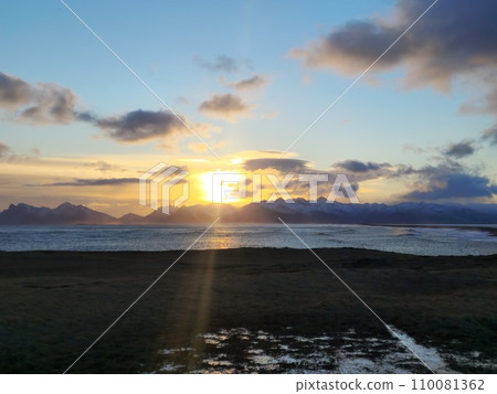 Arctic lake landscape at sunset with golden sky and snowy mountains, scandinavian wild nature creating fantastic scenery. Massive ocean beachfront around icelandic countryside. Arctic lake landscape at sunset with golden sky and snowy mountains, scandinavian wild nature creating fantastic scenery. Massive ocean beachfront around icelandic countryside. 110081362