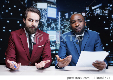 Diverse reporters covering new topics on midnight talk show, broadcasting latest events worldwide. Journalists team presenting live information from media papers, read headlines. 110081375