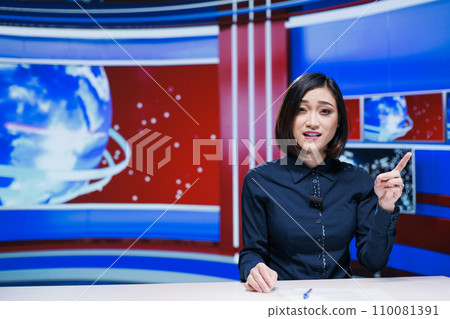 Asian tv host presenting daily news on live broadcast, discussing about latest events happening in the city. Journalist reading media headlines and giving important information to viewers. 110081391