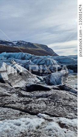 Glacier hiking vatnajokull ice cap in iceland with freezing cold icy blocks on scandinavian big lake, icelandic landscape. Majestic arctic icebergs near brown frosty hills and snowy fields. 110081474