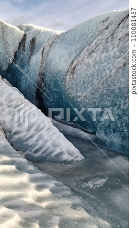 Vatnajokull glacier ice mass in nordic region, spectacular ice rocks with large caves around snowy mountain chain. Majestic frozen icebergs fragments floating on lake, scenic route. 110081487