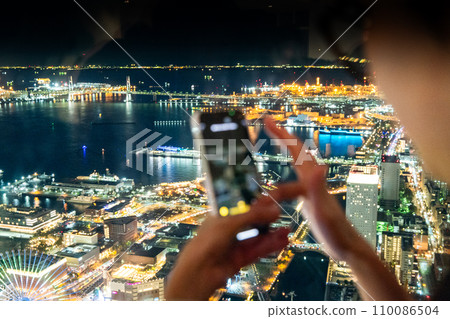A woman taking pictures of the night view of Yokohama 110086504