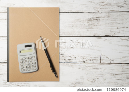 A notebook with a simple plain cover, a pen, and a calculator A notebook with a simple plain cover, a pen, and a calculator 110086974