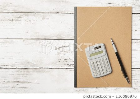 A notebook with a simple plain cover, a pen, and a calculator A notebook with a simple plain cover, a pen, and a calculator 110086976