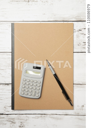 A notebook with a simple plain cover, a pen, and a calculator A notebook with a simple plain cover, a pen, and a calculator 110086979