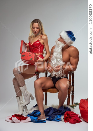 Tied up muscular Santa Claus giving gift to a woman in red lingerie 110088370