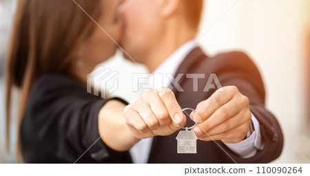 Happy couple shows keys to new apartment and kisses in agency Happy couple shows keys to new apartment and kisses in agency 110090264