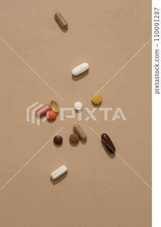 Top view of pills of different shapes and colors randomly placed on a brown background. Functional foods are foods used to support the function of organs in the human body. Top view of pills of different shapes and colors randomly placed on a brown background. Functional foods are foods used to support the function of organs in the human body. 110091287