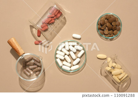 Pills of different colors are contained in glassware on a pastel background. Medicines are commonly used to support the treatment of various diseases. Pills of different colors are contained in glassware on a pastel background. Medicines are commonly used to support the treatment of various diseases. 110091288