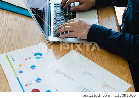 Hands of a man operating a computer and smartphone 110091360