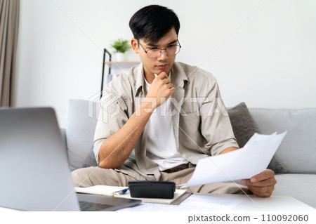 Man is calculating annual tax with calculator and filling form of Individual Income Tax Return. Season to pay Tax and Budget planning concept. 110092060