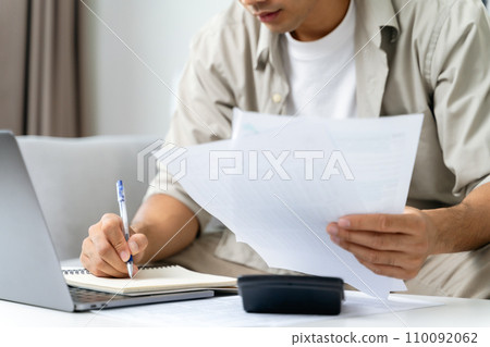 Man is calculating annual tax with calculator and filling form of Individual Income Tax Return. Season to pay Tax and Budget planning concept. 110092062