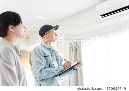 Asian worker inspecting air conditioner 110092349