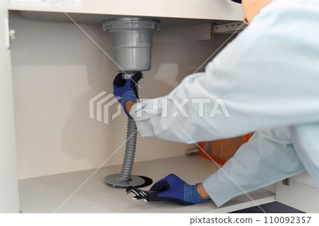 Plumber inspecting water equipment 110092357