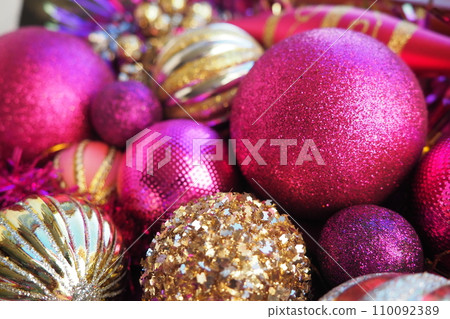 New Year's Christmas balls, tinsel and decorations close up. Decorations of golden, pink, lilac, purple, violet. Striped Christmas balls. Festive beautiful colorful background. Home holidays design. 110092389