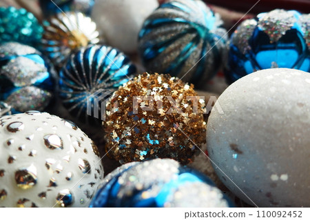 New Year's Christmas balls and decorations close up. A lot of decoration of golden, blue, yellow, white, silver. Striped Christmas balls lie on surface. Festive beautiful colorful background. Design. New Year's Christmas balls and decorations close up. A lot of decoration of golden, blue, yellow, white, silver. Striped Christmas balls lie on surface. Festive beautiful colorful background. Design. 110092452