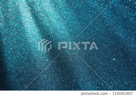 Oblique rays of light on a blue surface. Bokeh, dust particles, reflection and magical glow. Festive shining background. New Year, Christmas, birthday. Plastic card design. Cosmic photons from space 110092807