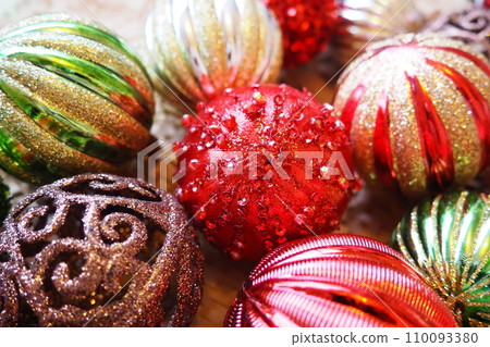 New Year's Christmas balls and decorations close up. A lot of decor of gold, red, yellow, brown, green, silver. Striped Christmas balls lie in a bunch. Festive beautiful colorful background. Design 110093380