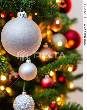 Beautiful red, gold, silver, yellow, beige shiny and matte Christmas balls shine on a spruce branch. Happy New Year. Merry Christmas. Christmas background - baubles and branch of spruce tree. Beautiful red, gold, silver, yellow, beige shiny and matte Christmas balls shine on a spruce branch. Happy New Year. Merry Christmas. Christmas background - baubles and branch of spruce tree. 110093541