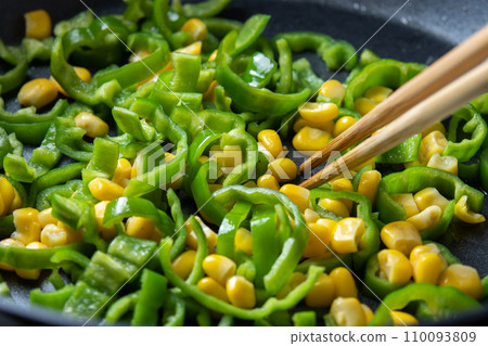 青椒和玉米粒在煎鍋裡翻炒的烹飪場景。 110093809