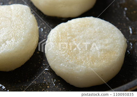 A cooking scene where mochi (round mochi) is fried in a frying pan. 110093835