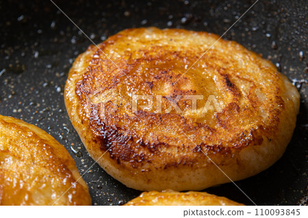 A cooking scene where mochi (round mochi) is fried in butter and soy sauce in a frying pan. Leftover mochi remake image. 110093845