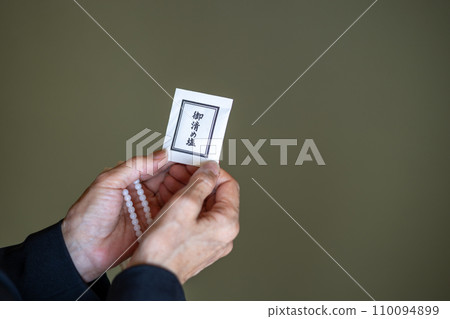 A woman's hands after a funeral, holding rosary beads and purifying salt. A woman's hands after a funeral, holding rosary beads and purifying salt. 110094899