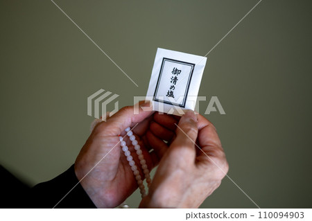 A woman's hands after a funeral, holding rosary beads and purifying salt. A woman's hands after a funeral, holding rosary beads and purifying salt. 110094903