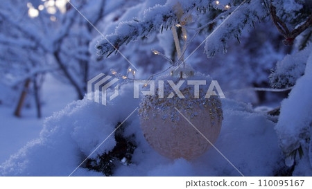 Decorated christmas tree outside with lights covered with snow 110095167