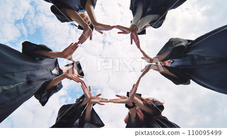 College graduates make a circle of their hands. 110095499