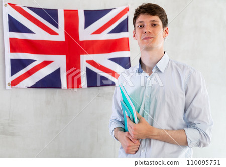 Male student with notebooks in his hands against background of the UK flag 110095751