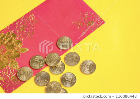 Top view of Chinese New Year red packets and golden coins on yellow cover background 110096448