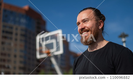 Portrait of a Caucasian bearded man on a basketball court outdoors.  110096882